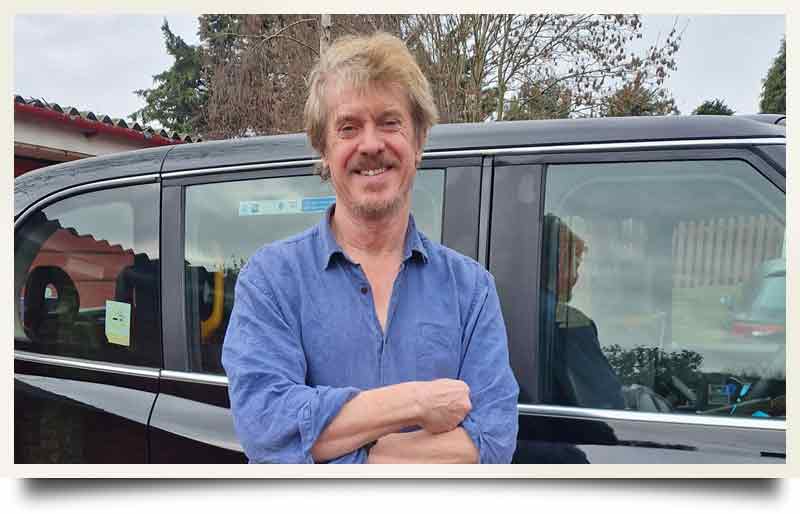 Standing arms crossed by his London Black Cab.