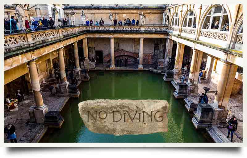 Tourists at street level looking down to the water and stone tabley with inscription 'No Diving' in a Roman font.