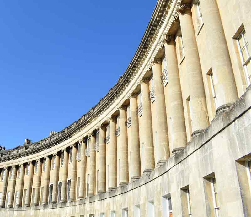 Curved Georgian facade from the ground beneath a blue sky.