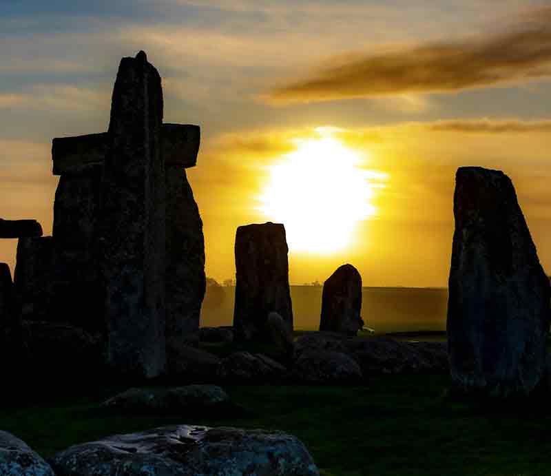 The standing stones in silhouette with the rising sun.